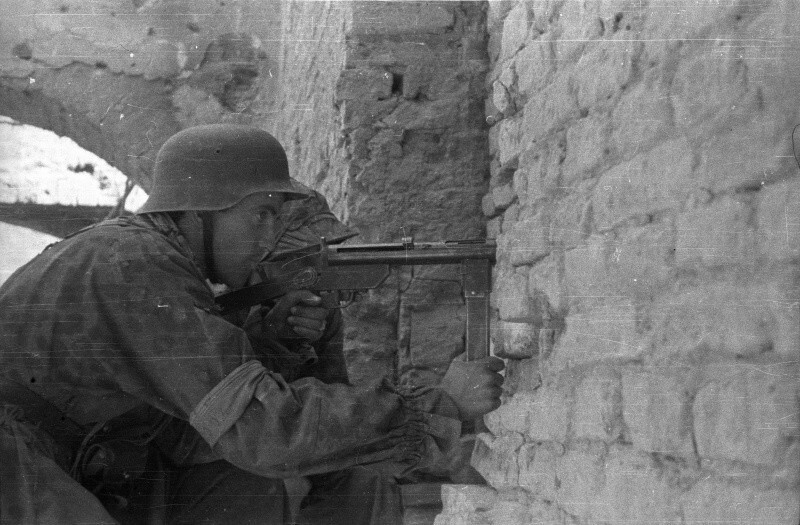 Варшавский повстанец Ежи Сикорский (Jerzy Sikorski) роты «Анна» батальона «Густав» с 9-мм пистолетом-пулеметом «Блыскавица» (Błyskawica) у стены дома на углу улиц Слепа (Ślepa) и Пивна (Piwna).