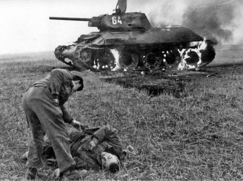 Немецкий солдат обыскивает погибшего советского солдата-пехотинца. 