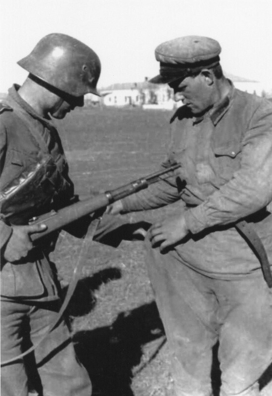 Немецкий солдат проверяет карманы сдавшегося в плен красноармейца. 