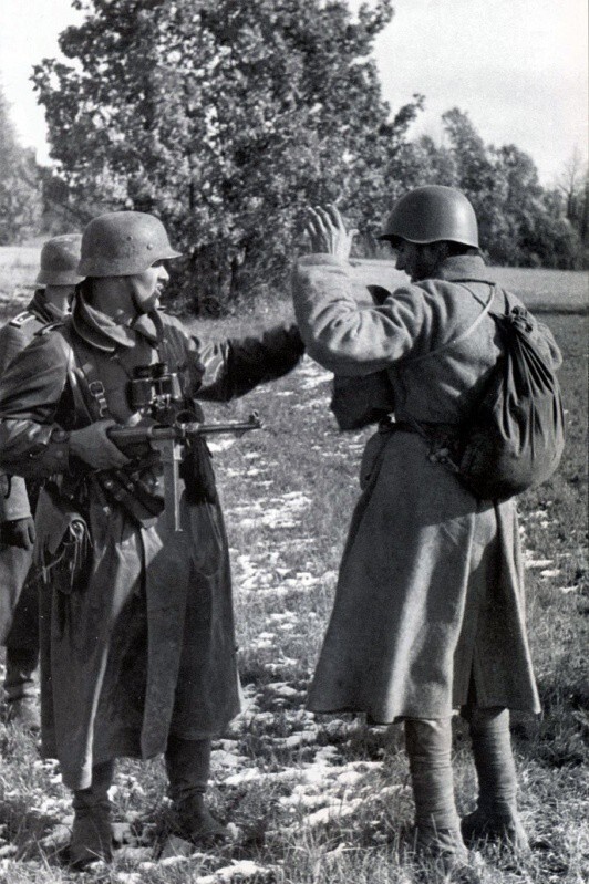 Немецкий унтер-офицер обыскивает сдавшегося красноармейца.