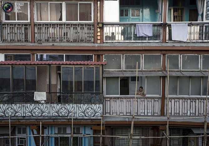 Женщина стоит на балконе своей квартиры