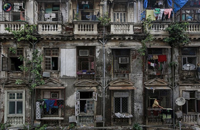 Женщина развешивает бельё в старом доме в Мумбаи