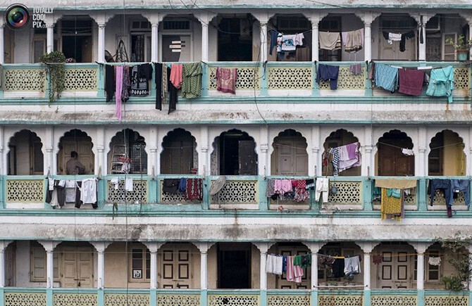 Мужчина запирает дверь своей квартиры в старом доме в Мумбаи