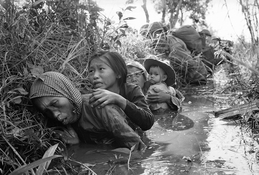 Женщины и дети забиваются в грязный канал, как они укрыться от пожара на Бао Трай, примерно в 20 милях к западу от Сайгона. 1 января 1966 года.