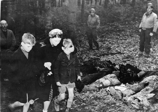 3 мая 1945 года Немка закрывает глаза сыну, когда они проходят мимо эксгумированных тел 57 русских солдат.