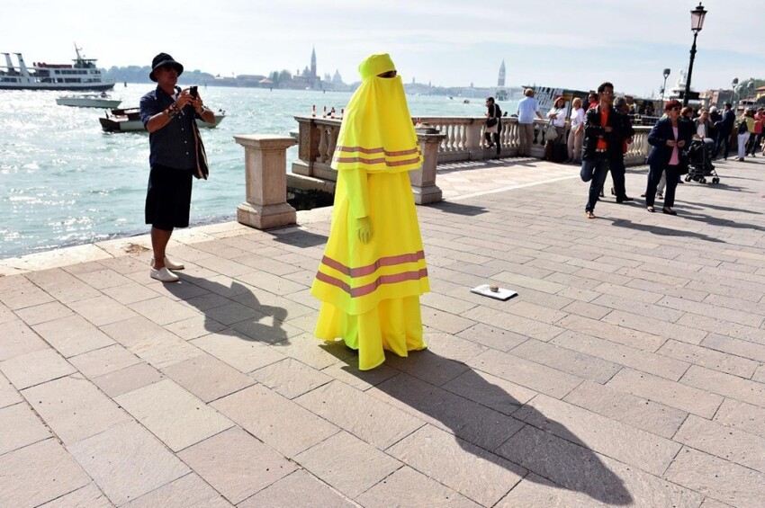 Женщина в желтой бурке показывает перфоманс «High Visibility Burqa» возле места проведения Венецианской биеннале
