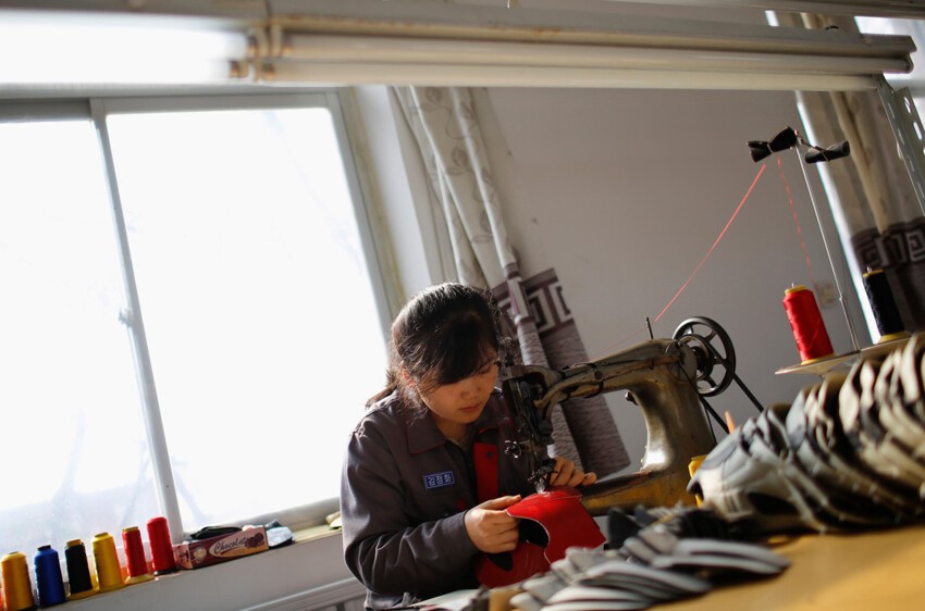 Северокорейская девушка работает на обувной фабрике в деревне Дандон.