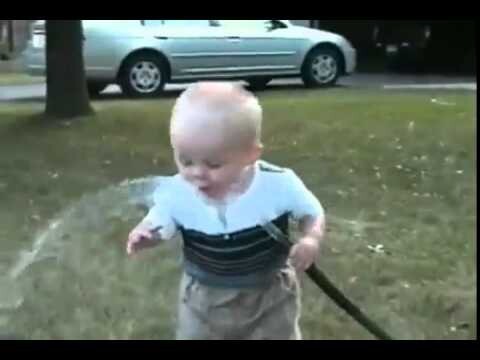 Малыш пытается попить водички из шланга 