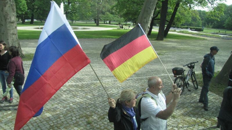 На подъездах к парку народ встречает вот такая милая пара, которая машет российским и немецким флагом в знак мира и дружбы..