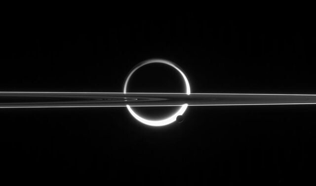 Кольца Сатурна, пересекающие Титан, недалеко от южного полюса которого виднеется Энцелад.