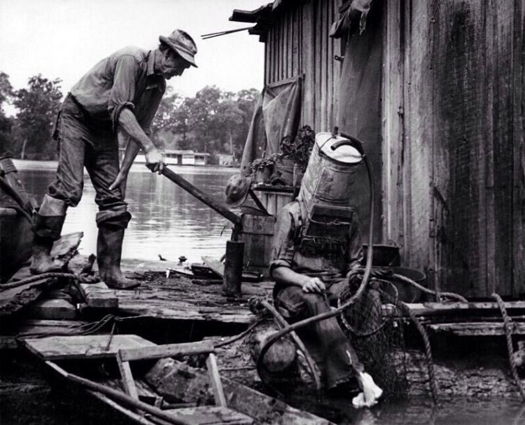 Ловец жемчуга на Миссисипи готовится к очередному "заходу" на дно. В качестве шлема - старый топливный бак от автомобиля. В таком аппарате он мог погружаться на глубину до 21 метра и находится под водой до 1,5 часов, 1938 год