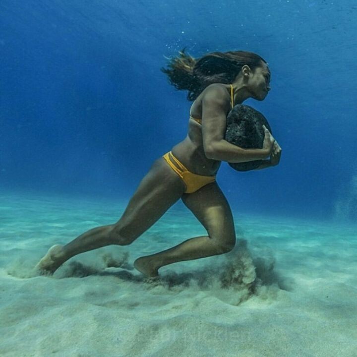 2. Серфингистка ходит по морскому дну с 20-килограммовым камнем, тренируя сопротивляемость ударам волн