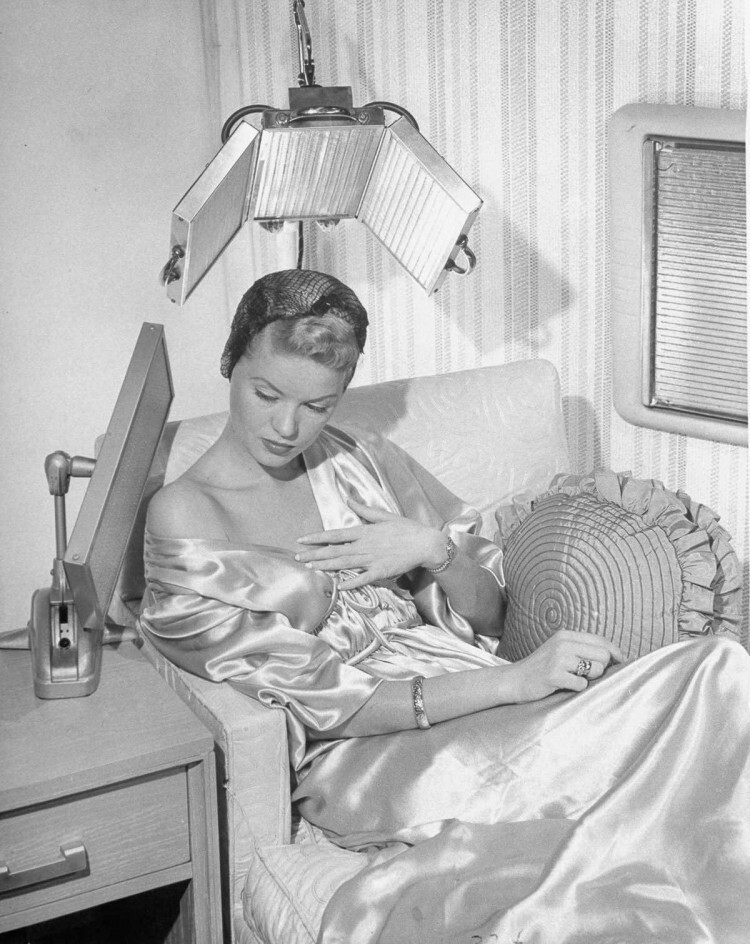 1948 г. Женщина использует тепловой светильник и фен из стекла.