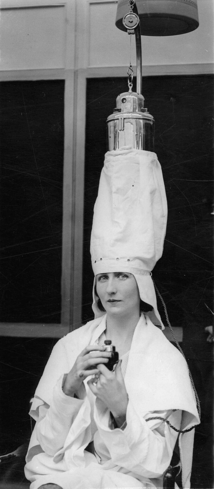 1930 г. Женщина демонстрирует аппарат для обработки волос паром на парикмахерской выставке в Лондоне.