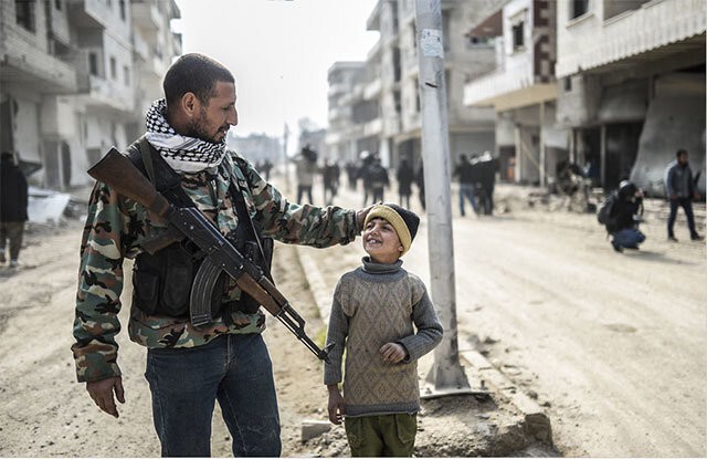 Курдский боец со своим сыном на улице Кобани (Сирия) после восстановления контроля над городом, захваченным ИГИЛ