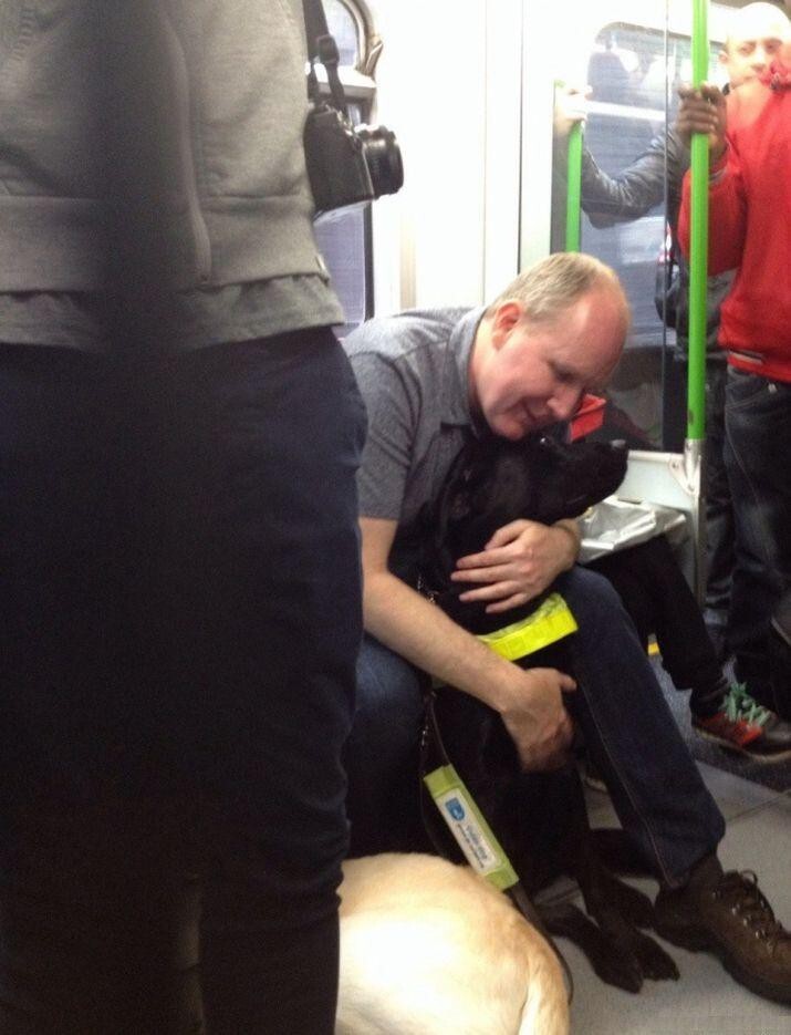 Слепой мужчина обнимает свою собаку-поводыря