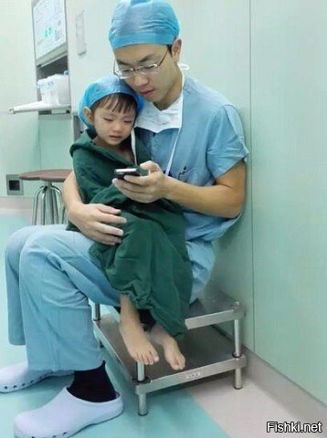 Хирург успокаивает плачущую девочку перед операцией, просматривая вместе с не...