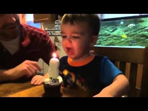Папа помог своему сыну задуть свечу на торте  