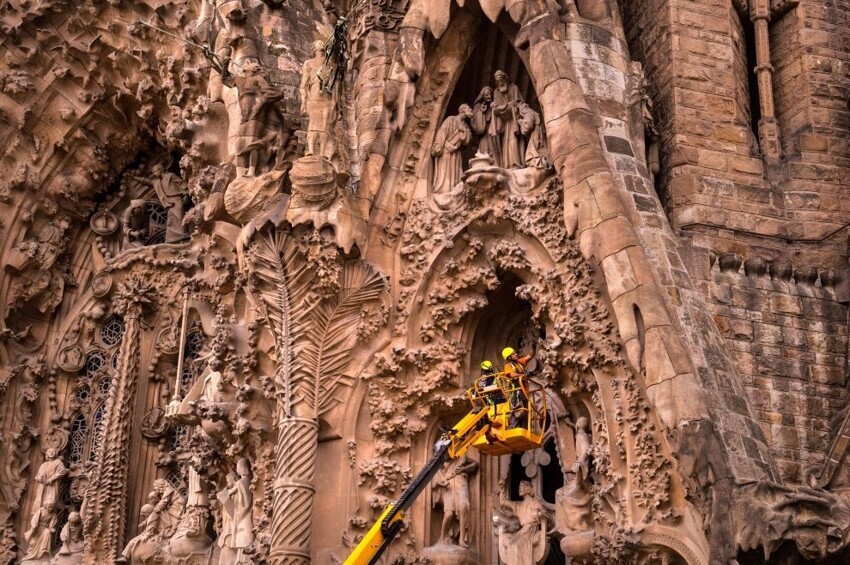 Рабочие трудятся у фасада Храма Святого Семейства в Барселоне.