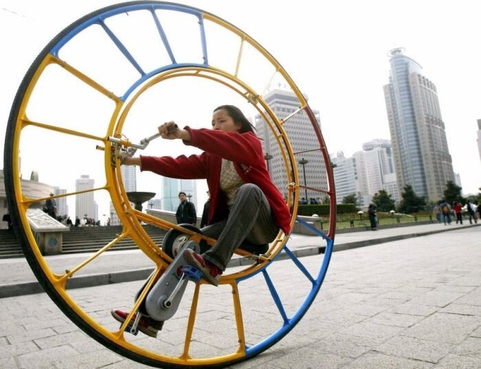 Женщина едет на одноколесном велосипеде в парке в Шанхае. Одноколесный велосипед был разработан в начале 21-ого века китайским изобретателем Ли Йонгли
