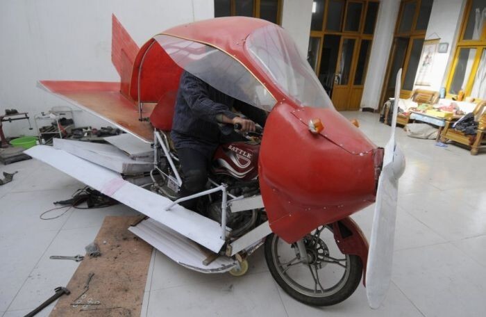 Чжан Ксюйлин сидит внутри своего самодельного самолета, вокруг мотоцикла
