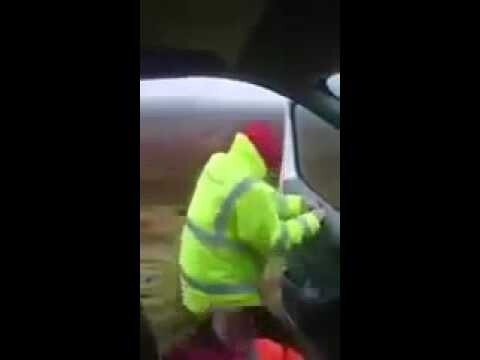 Шотландец пытается закрыть дверь автомобиля во время штормового ветра  