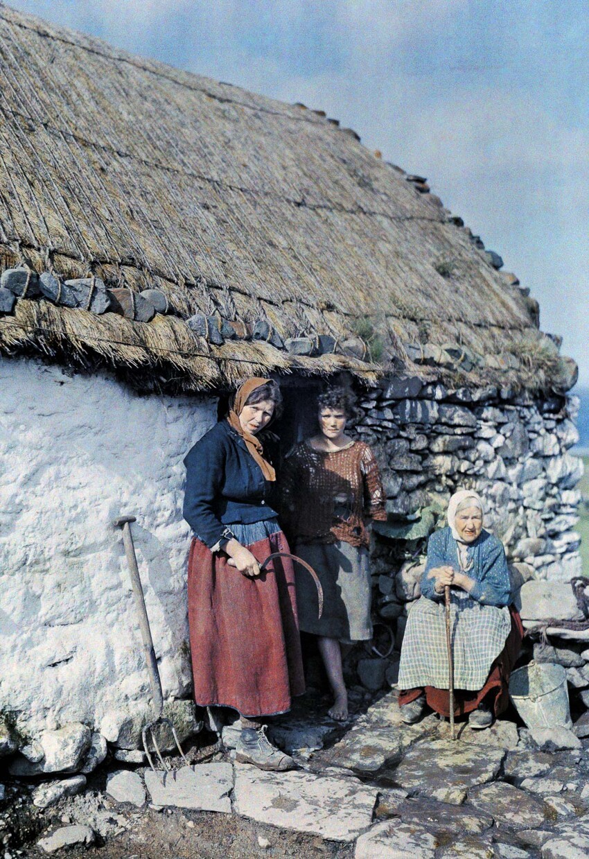 Три поколения крестьянок стоят возле своего каменного дома.