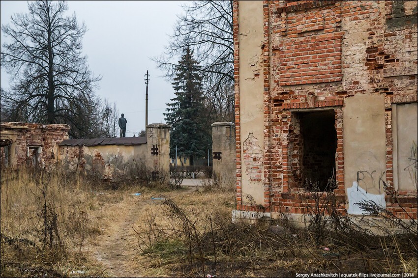 Буквально за забором памятник Ленину. Он укоризненно смотрит на развалины дома напротив своего сквера.