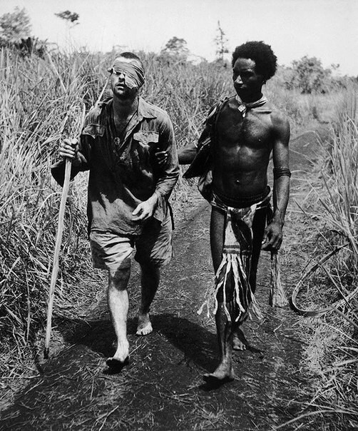 Коренной житель Папуа — Новой Гвинеи выводит раненого австралийского солдата из степи. Вторая мировая, 1942 г.