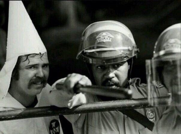 Чёрный полицейский защищает членов Ку-Клукс-Клана от протестующих, 1983 год
