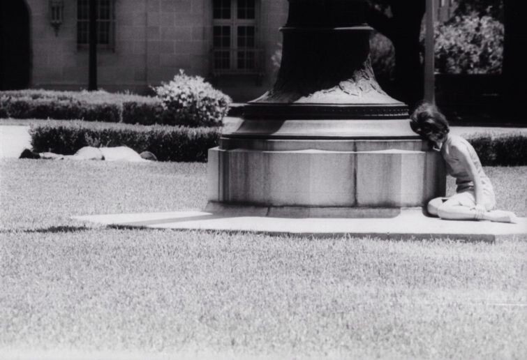 Девушка прячется за статуей, в нескольких метрах от неё лежит раненый снайпером Чарльзом Уитманом человек. Уитмен забаррикадировался на самом верху 27-этажной башни Техасского университета и в течение полутора часов стрелял из винтовки с оптическим п