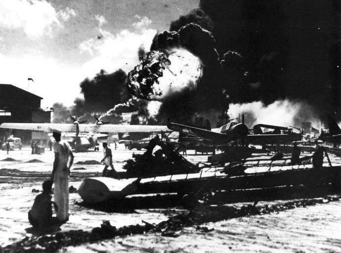 Аэродром на базе ВМС США на острове Форд острова. На заднем фоне видно пламя от горения морских судов после нападения японцев, 7 декабря 1941 года..