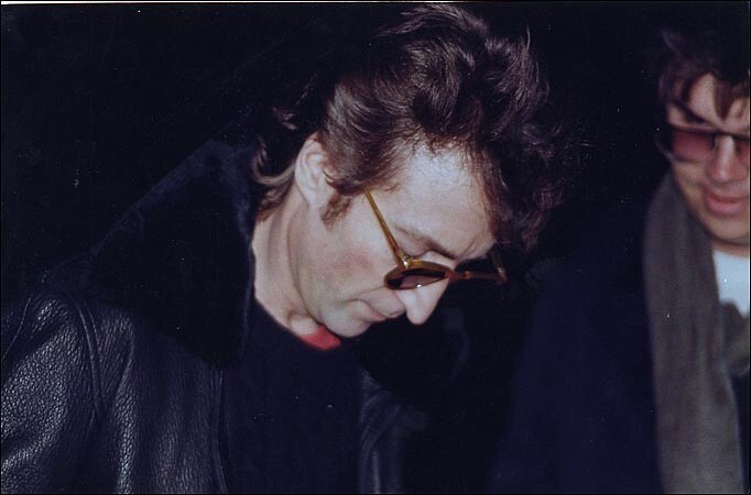Леннон подписывает копию Double Fantasy Чэпмену (справа) за несколько часов до смерти..