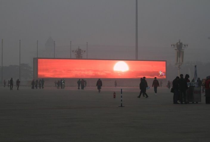 8. Жители Пекина из-за сильного смога любуются рассветом у специального экрана.