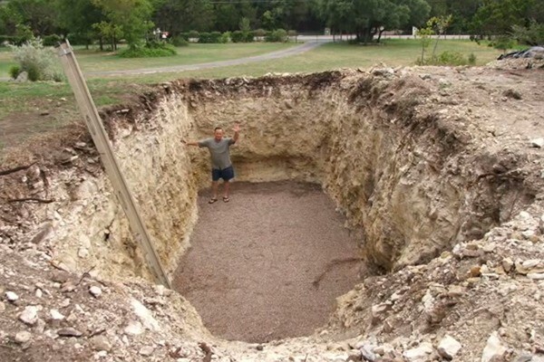 Он выкопал яму глубиной больше, чем высота контейнера, и уложил на дно ямы слой гравия.