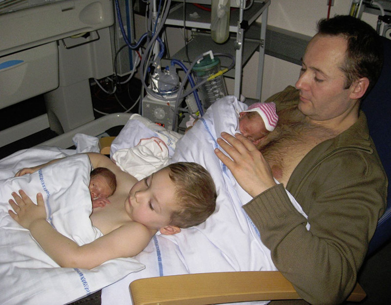 Фото молодого отца и его старшего сына, выложивших на грудь новорожденных близняшек, взорвало Сеть