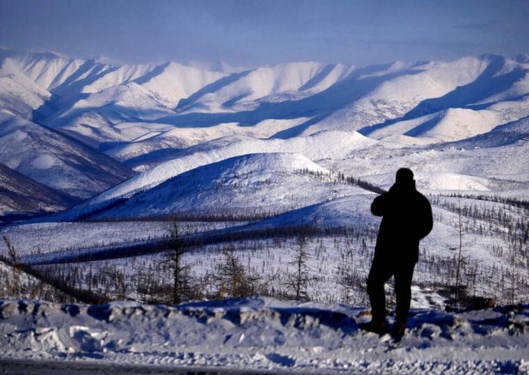 Руслан смотрит вперед, в то место, где Колымское шоссе поворачивает налево среди гор. Ясное солнечное утро, мы хорошо проводим время.