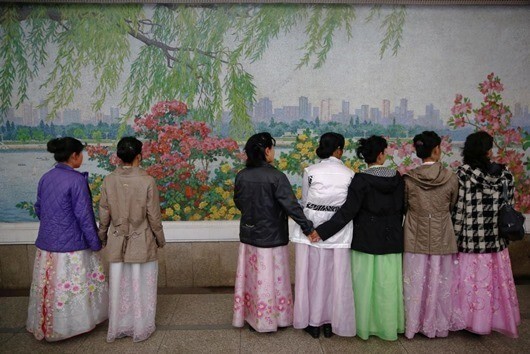 Женщины в традиционной одежде ждут прибытия поезда метро в центре Пхеньяна.