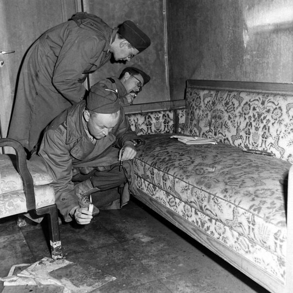 Корреспонденты при свете свечей рассматривают диван, на котором 30 апреля 1945 г. застрелился Гитлер (пятно крови - у дальнего подлокотника) 