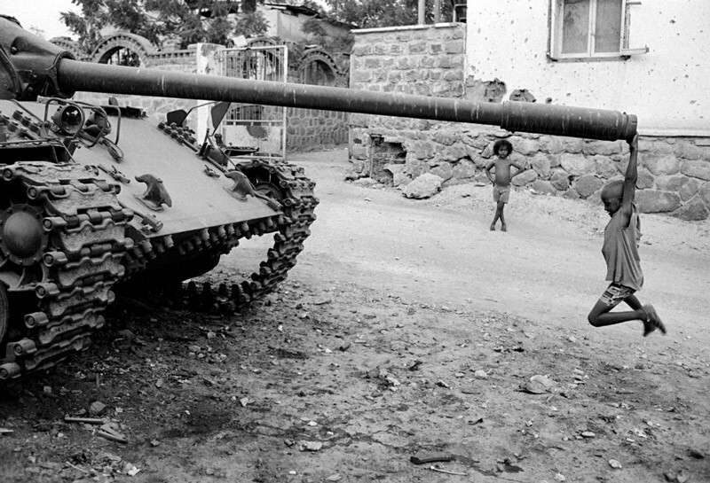 Африканский ребенок играет с заброшенным танком, 1991
