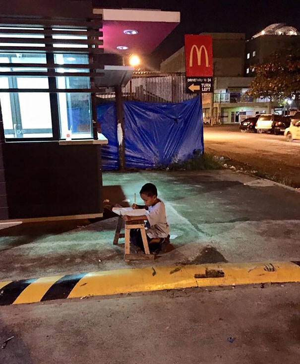 22. Бездомный мальчик делает уроки при свете от местного Макдональдса