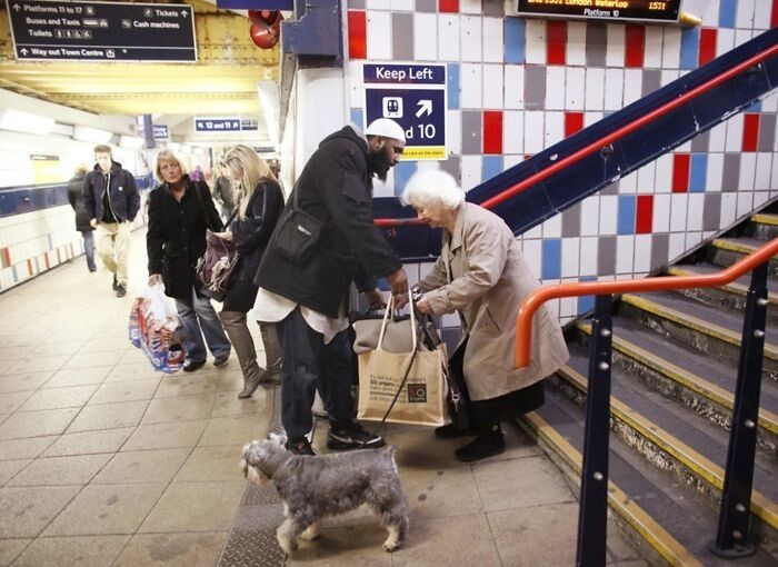 Мужчина помогает старушке нести сумки