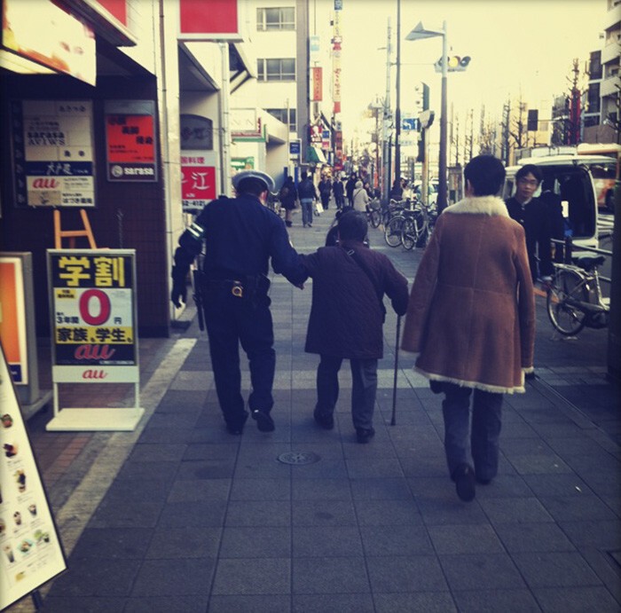 Японский полицейский помогает пожилой женщине