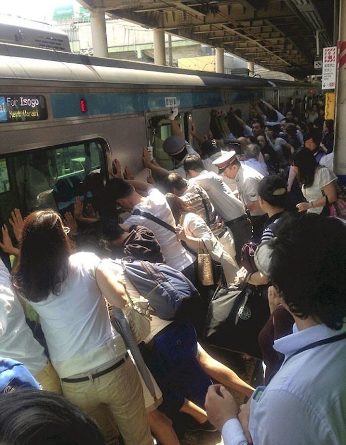 Люди на вокзале пытаются помочь человеку, зажатому между поездом и платформой