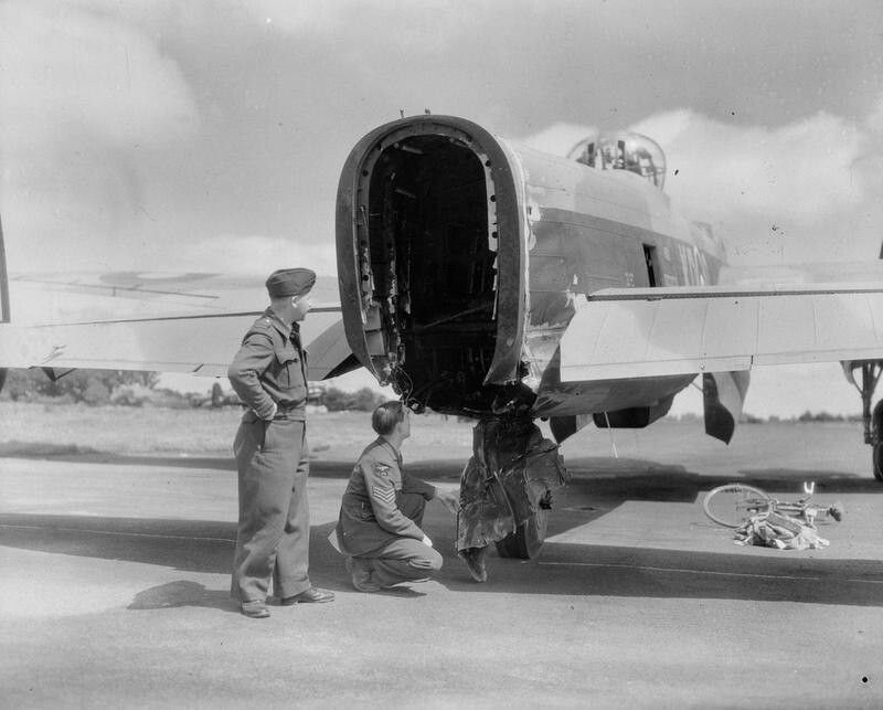 85. Британские лётчики осматривают повреждения хвостовой части бомбардировщика "Ланкастер" из 115-й эскадрильи