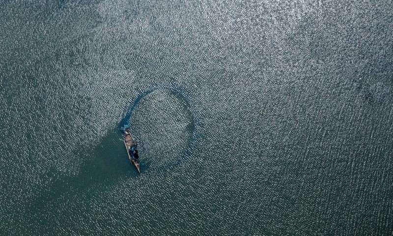 Это фотография реки Калиганга, сделанная по дороге из Маникганджа в Дакку. Рыбаки собирают из сетей свою добычу, а на воде видна легкая зыбь от ветра.
