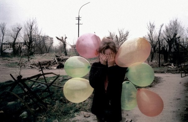 Девочка закрывает глаза от фотографа в центре разрушенного города Грозный, Чечня март 2002 года  