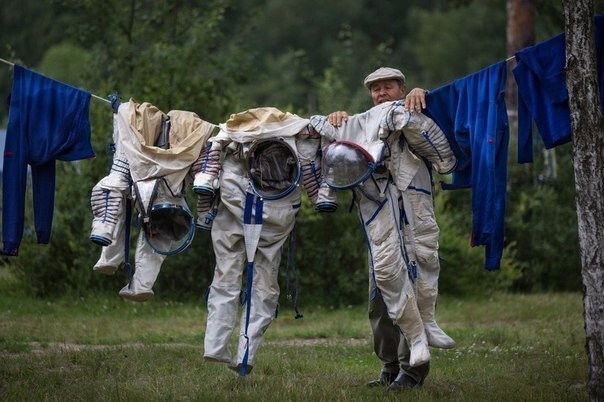 Сотрудник российского космического центра развешивает скафандры для просушки.