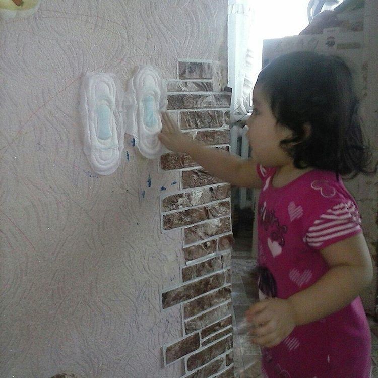 Ребёнок лепит прокладки на стену