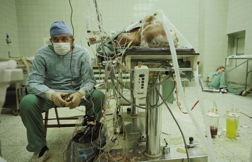 Кардиохирург Збигнев Релига следит за жизненными показателями пациента после 23-часовой операции по пересадке сердца. Помощник хирурга спит в углу (1987 г.)